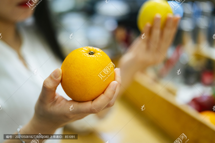 美丽的亚洲女人在超市挑选橘子和柠檬。健康食品选择。维生素C水果。