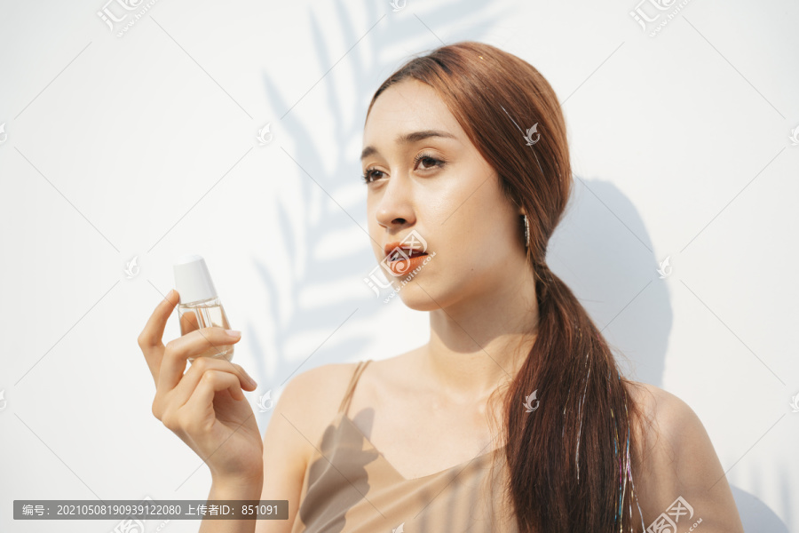 美丽迷人的黑发女子手持化妆品瓶产品。天然产物。化妆品概念。