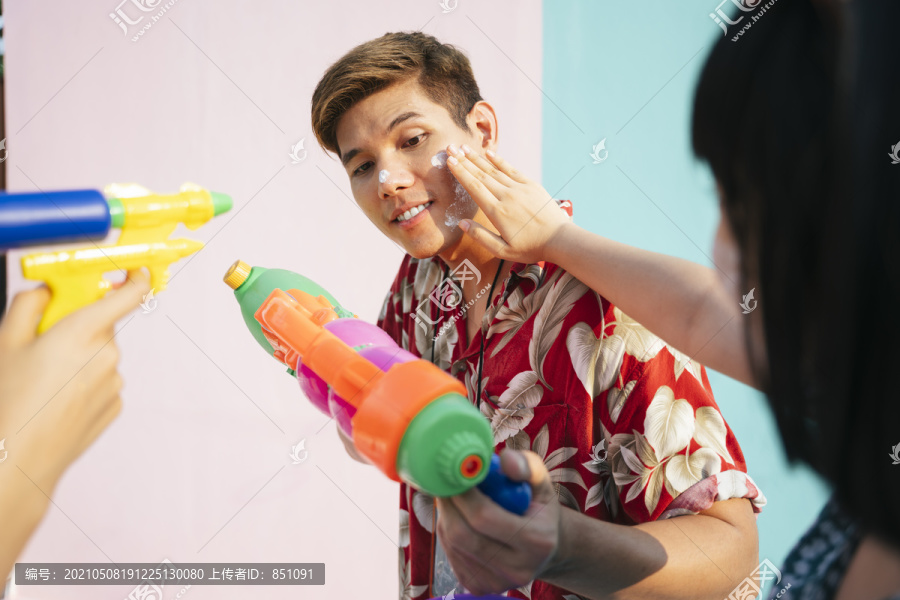 泰国当地男子在泼水节玩水枪。那个人脸上被湿粉拍了一下。