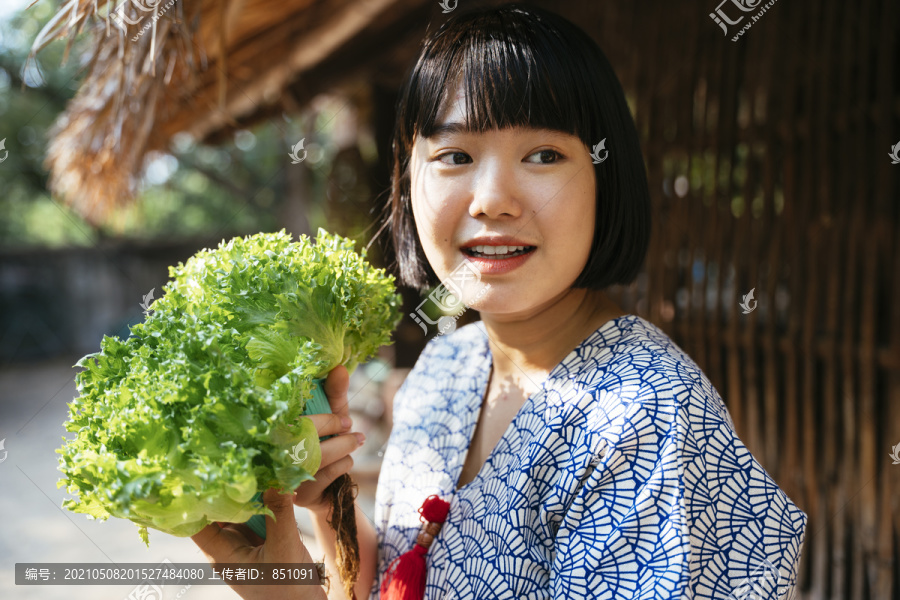 生态旅游——当地年轻农民手持绿色新鲜蔬菜从事农业经营。鲍勃发型女孩。素食主义者。