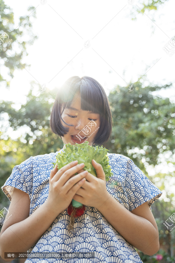 生态旅游-美丽的亚泰女子鲍勃发型手拿绿色新鲜蔬菜。蔬菜爱好者。健康食品。