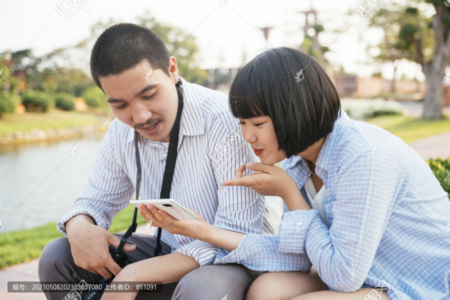 一对亚洲可爱的夫妇在镜头前看他们的照片。旅行者夫妇。