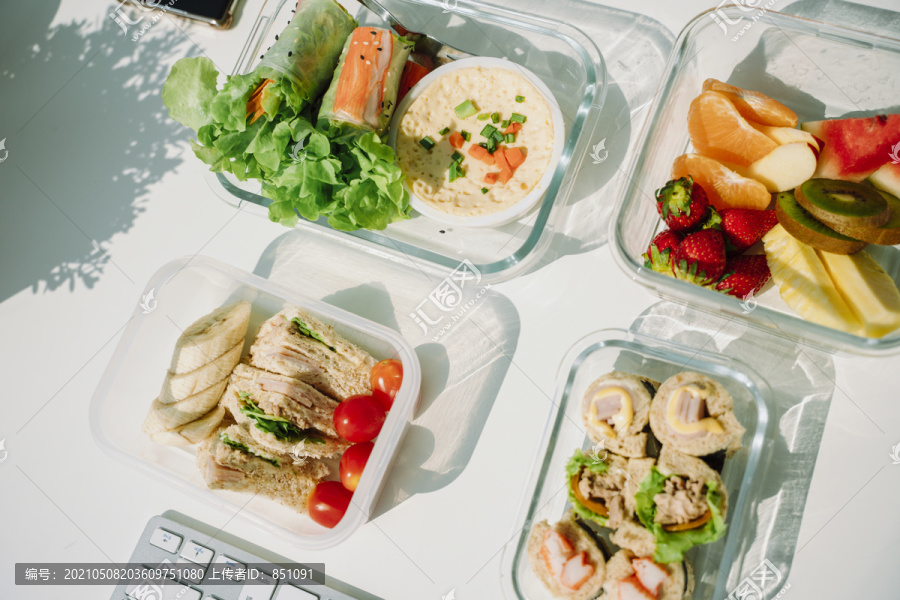 4个健康食品碗的顶视图，包括沙拉碗、春卷、三明治和水果。