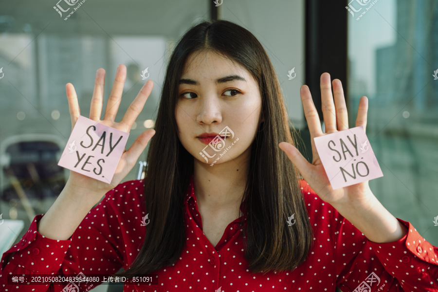 年轻漂亮的泰国亚裔女商人，穿着红衬衫，手上拿着纸。说是或说不。