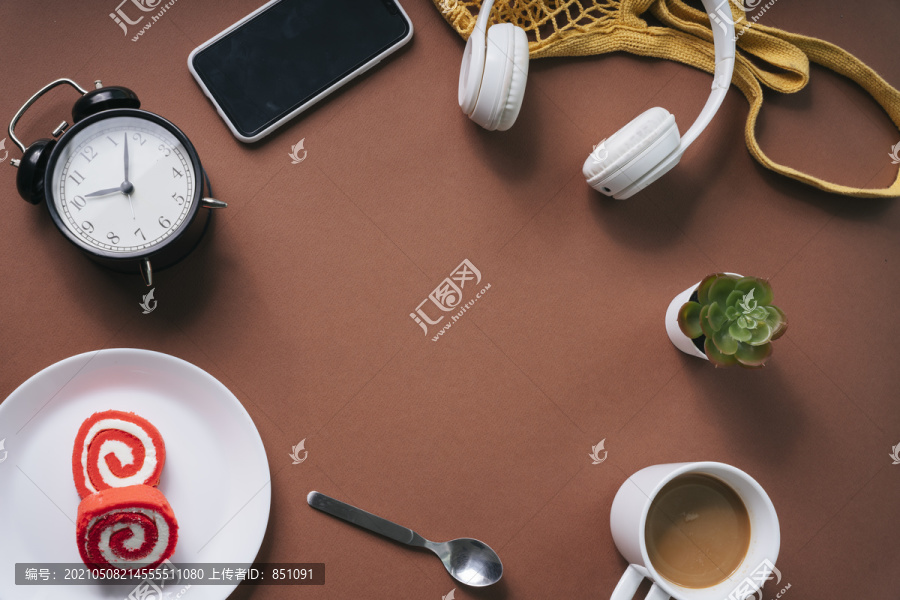 固定的。平铺的甜点，热咖啡，勺子，时钟，桌子，耳机，智能手机在棕色的桌子上。