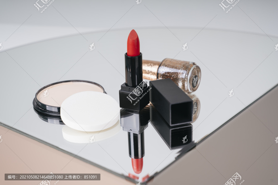餐桌上摆着奢华的化妆品。红色唇膏黑盒和粉扑。