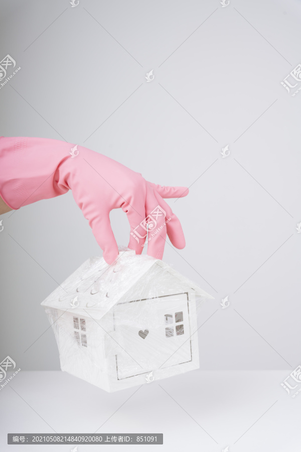 医生的手戴着粉色手套，手里拿着一个塑料包装的白宫玩具罩。医生从Covid-19那里救人。冠状病毒概念