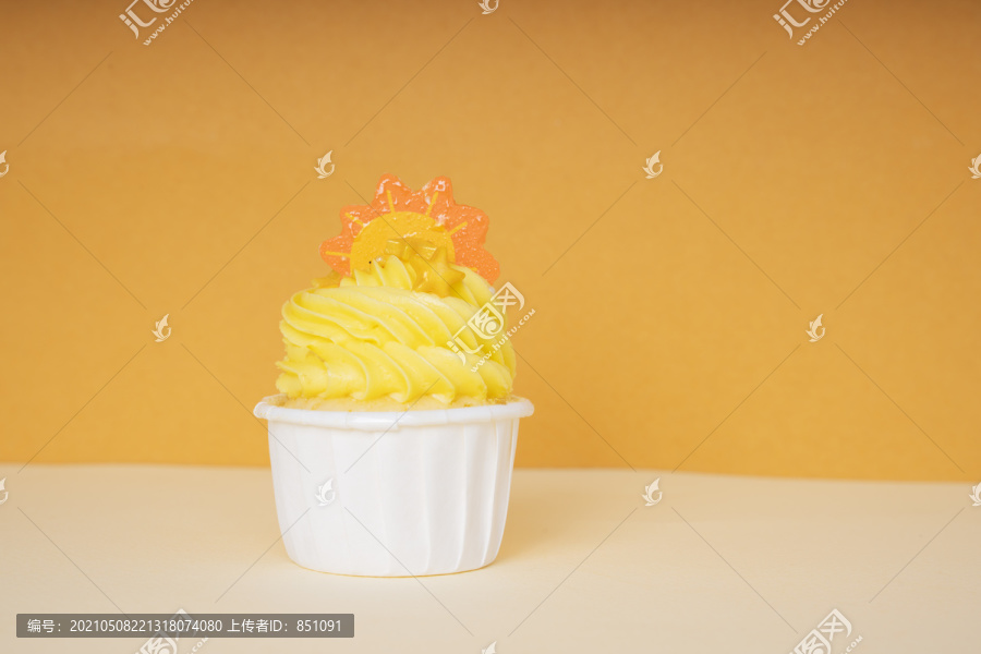 白色杯中的橙色纸杯蛋糕用一片橙色薄片装饰。复制空间。实体模型。