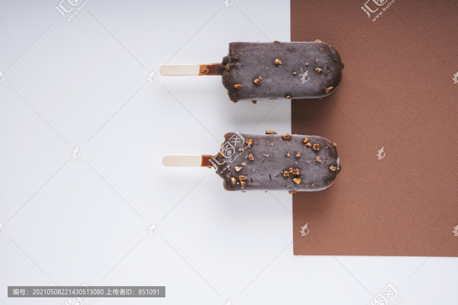 顶视图-巧克力榛子冰淇淋棒上的白色和棕色背景。两个。