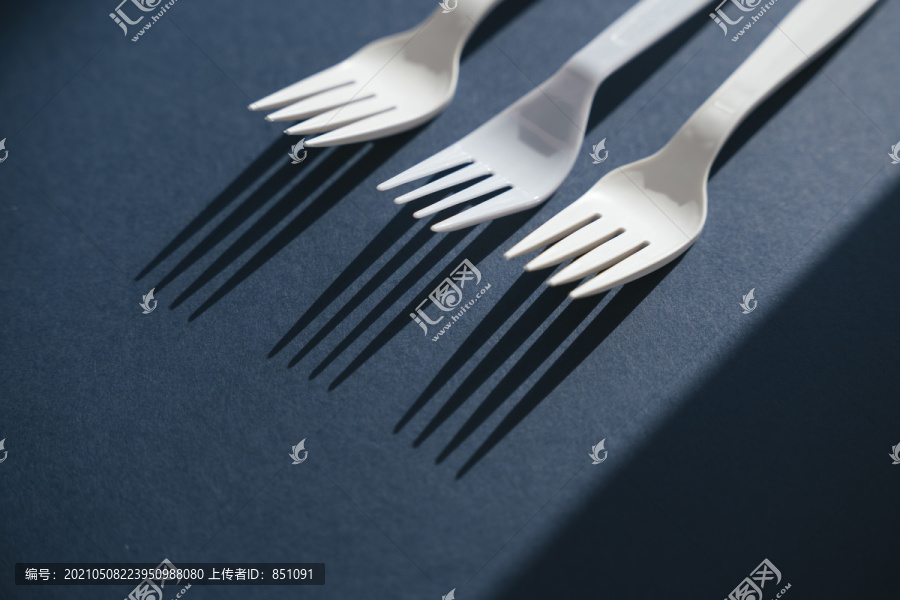 三个白色塑料餐具叉放在一起。