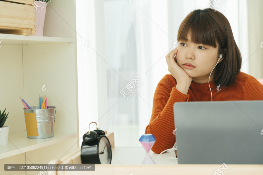 美丽的年轻亚泰黑短发女子在家拿着笔记本电脑学习感到无聊。