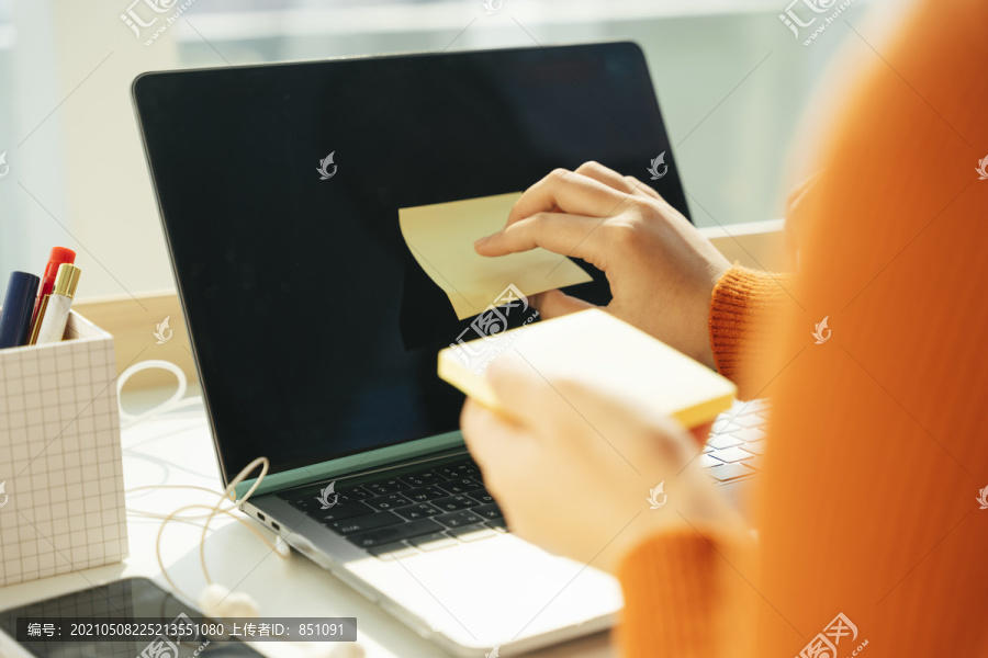 女学生在家学习后在笔记本电脑上贴便条。