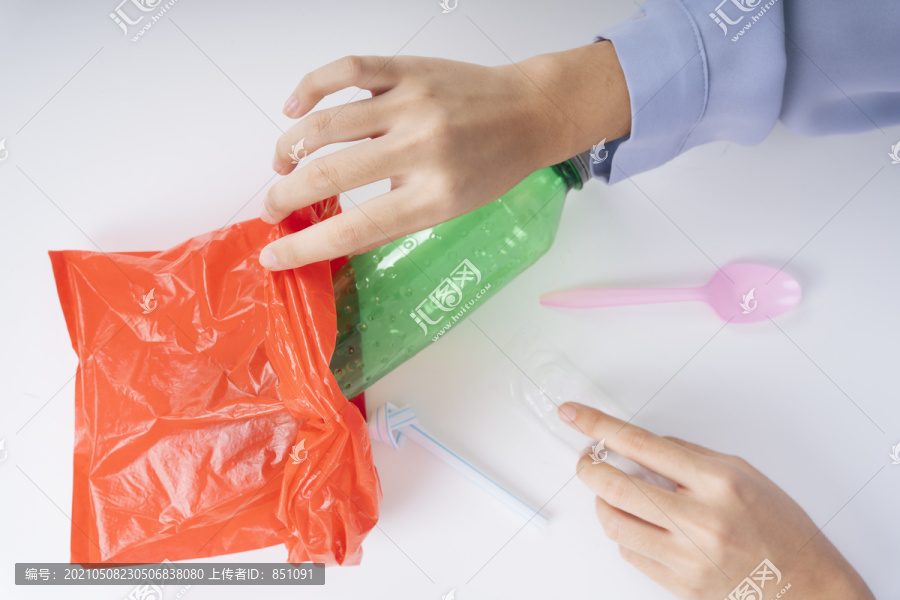 妇女手把塑料垃圾放进一个塑料袋中循环利用。