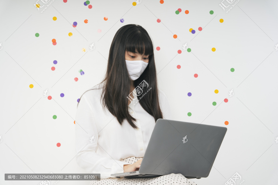 美丽的亚泰长黑发女子戴着白色口罩用笔记本电脑隔离白色派对背景。在家工作的概念。女商人用笔记本电脑工作
