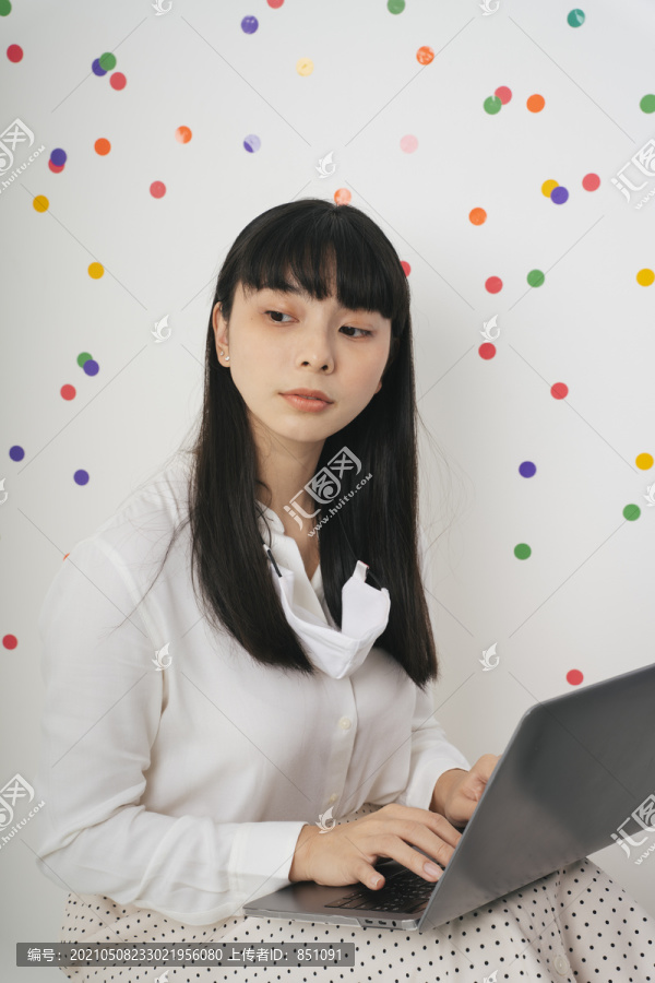 体贴美丽的亚泰黑长发白衬衫女人在家里用笔记本电脑工作。在家工作。