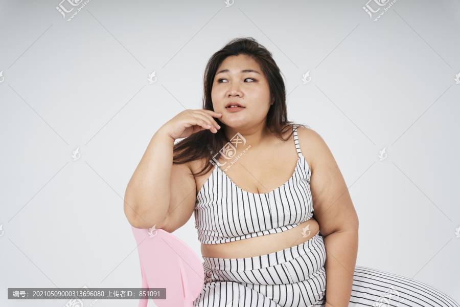 健康的亚洲胖女人坐在白色背景的椅子上的肖像。