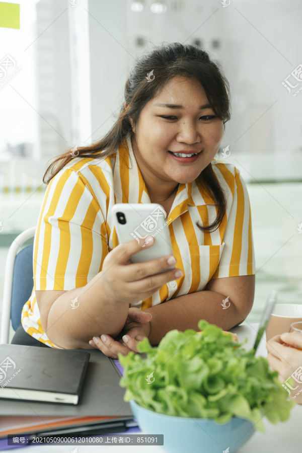亚洲胖女人通过智能手机上的应用程序订购健康食品。