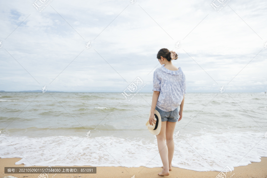 后景-年轻的亚洲旅行家妇女独自在沙滩上行走。