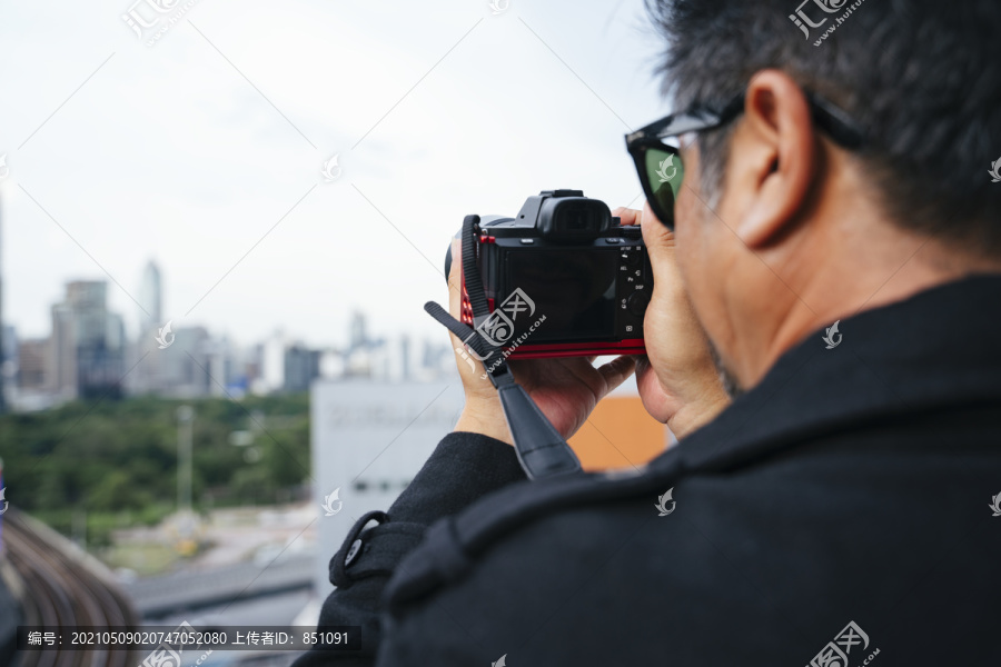 时尚写真——戴墨镜手持无镜相机的老年高级摄影师。