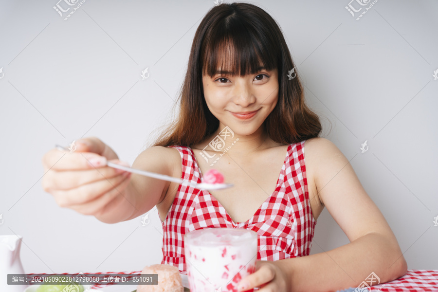 亚洲年轻女子用勺子吃菱角甜点。