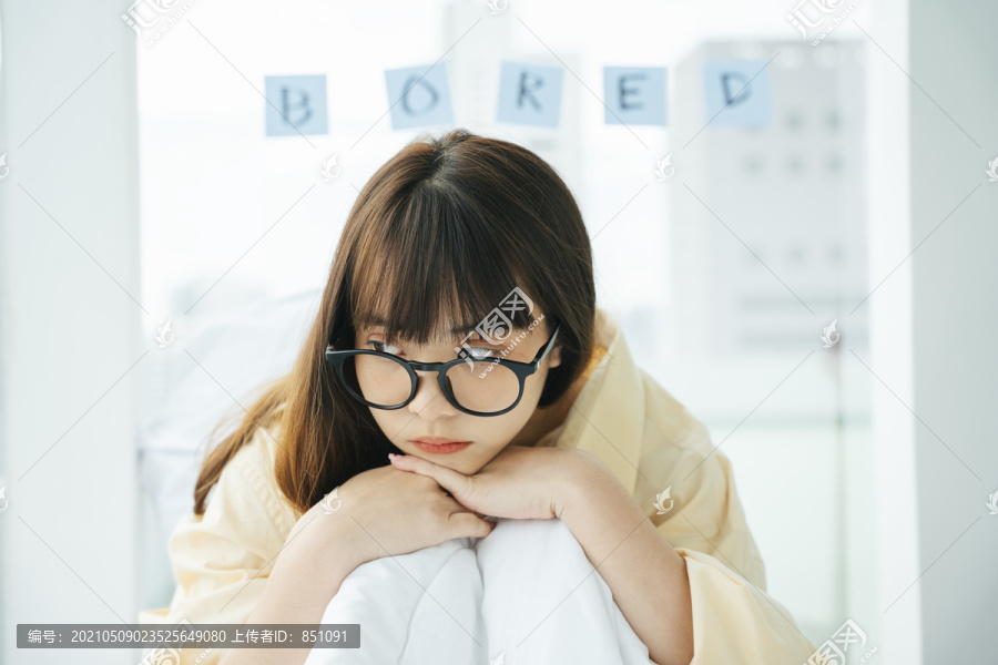 可爱的年轻亚洲黑发女子戴着眼镜躺在床上。无聊的女孩在沙发上放松。