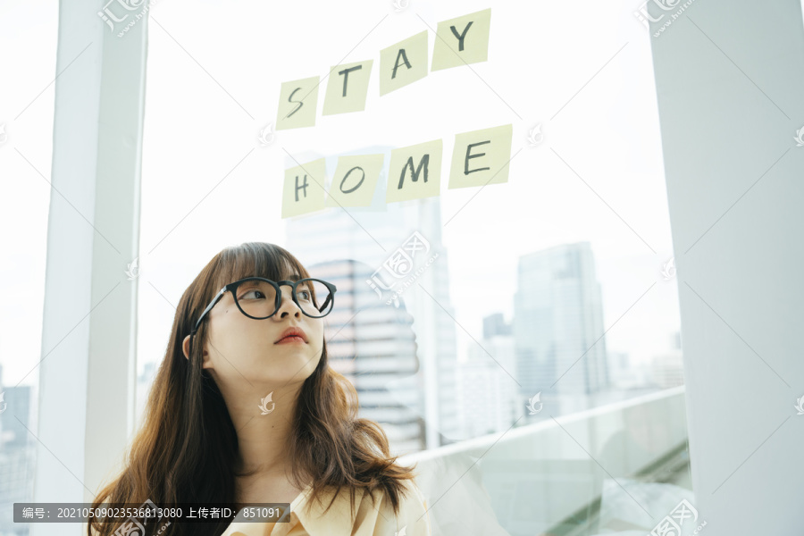 年轻的亚洲黑发女子戴着眼镜呆在家里，因为covid-19的爆发。