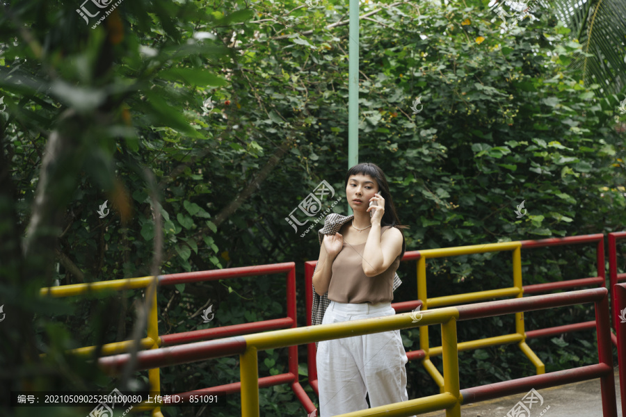 穿着正式衬衫的亚洲女商人在桥上打电话。