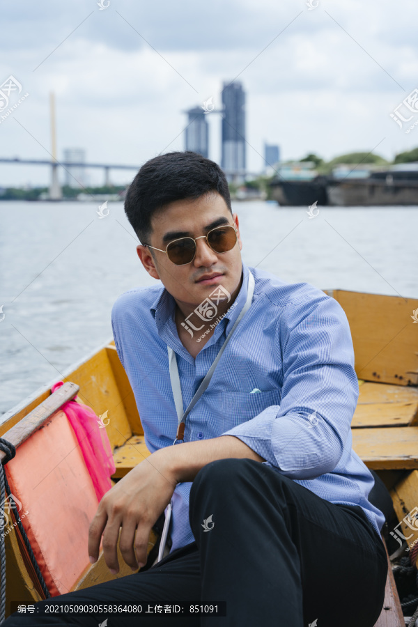 时尚写真-亚洲商人戴墨镜坐在曼谷的木船上。