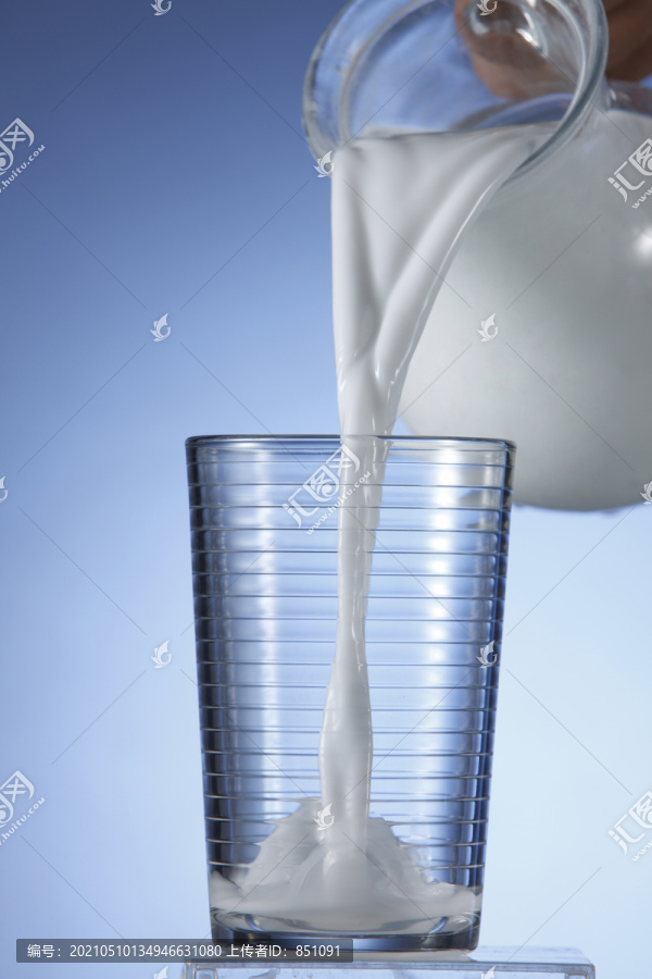 一壶牛奶倒进玻璃杯里。