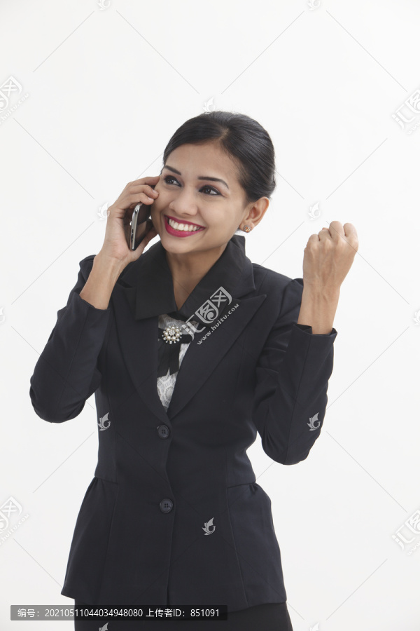 快乐的商务女性，在白色背景下兴奋地举起手臂，拿着手机