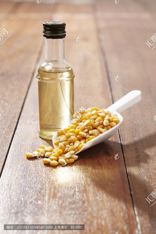 木桌上放着玉米和一瓶玉米油