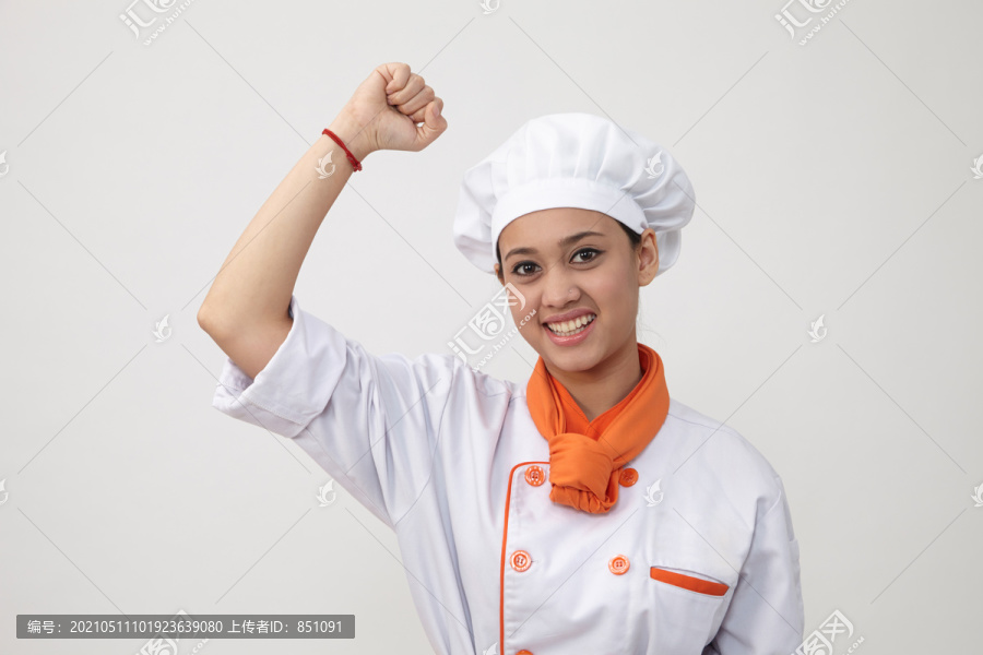 一位印度妇女的肖像，身穿厨师制服，手臂朝上