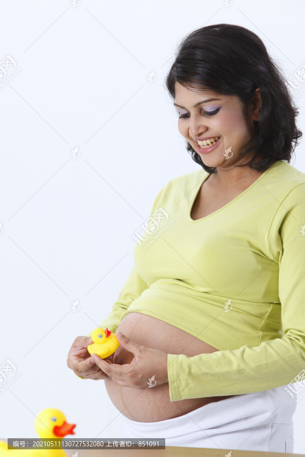 怀有身孕的妇女抱着一只黄色塑料玩具鸭。
