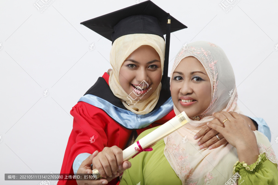 年轻的毕业生和母亲一起拿着毕业证书