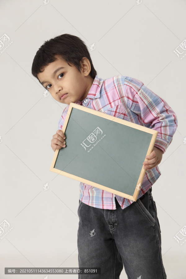 男孩拿着一块空白的黑板看着相机