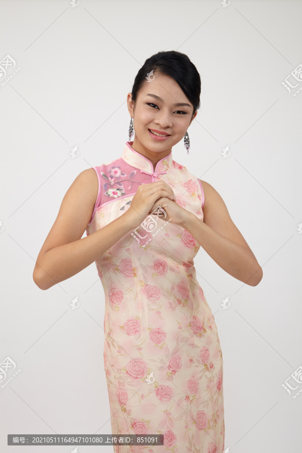 微笑的中国女子身着传统旗袍问候，摄影棚拍摄的白色背景上的孤立。