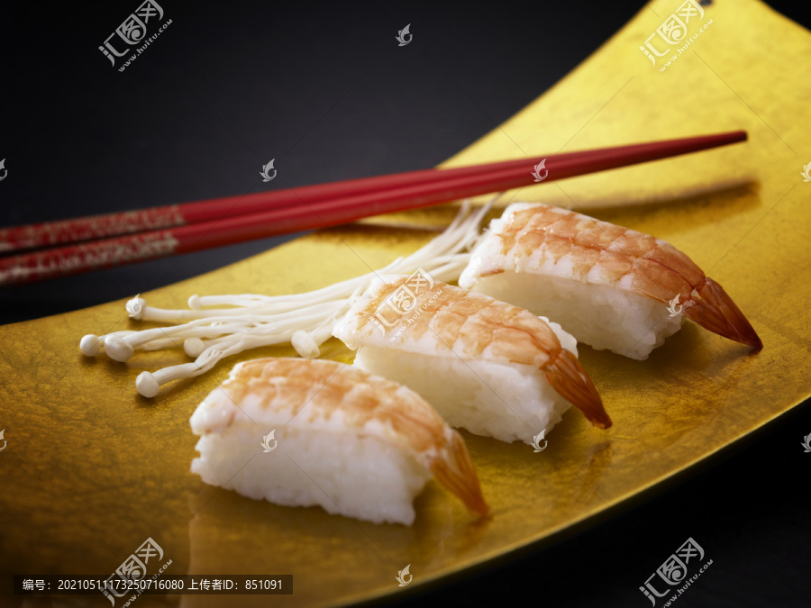 用筷子把虾寿司放在盘子里