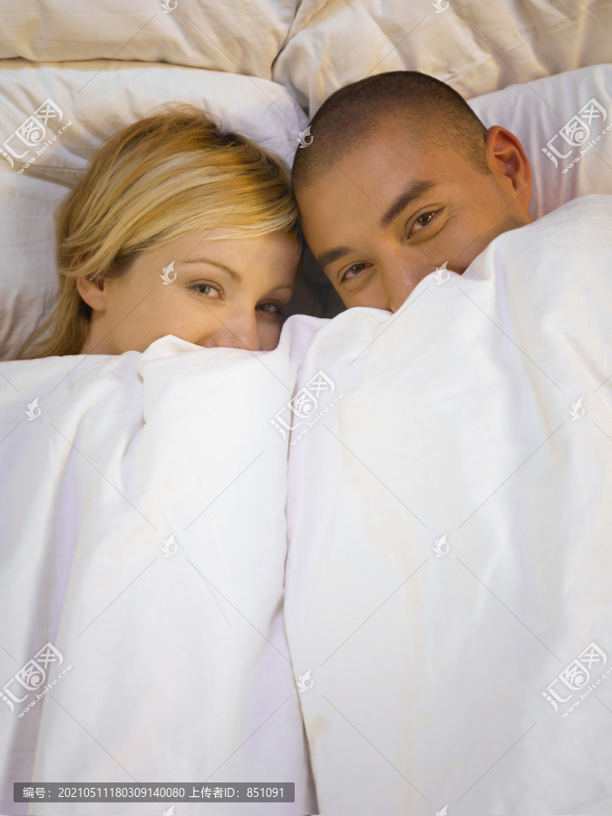 一男一女躺在床上，脸上蒙着毯子