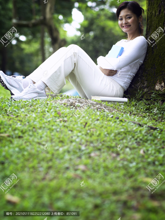 把注意力集中在草地上，女人坐在树下