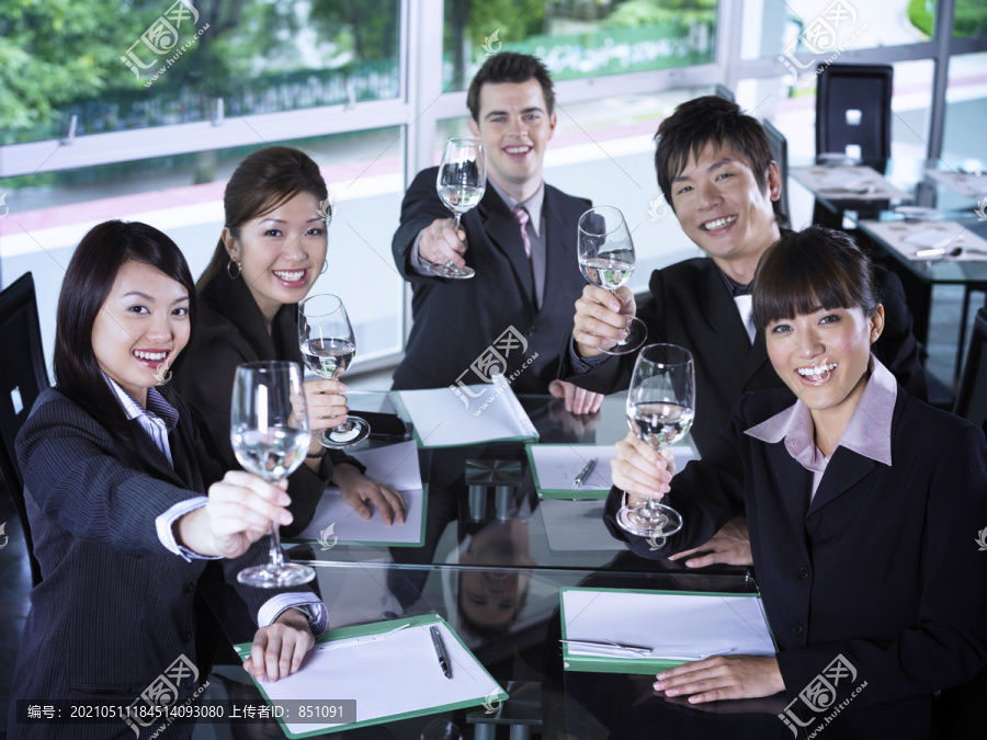 一群商界人士微笑着在饭桌旁举杯