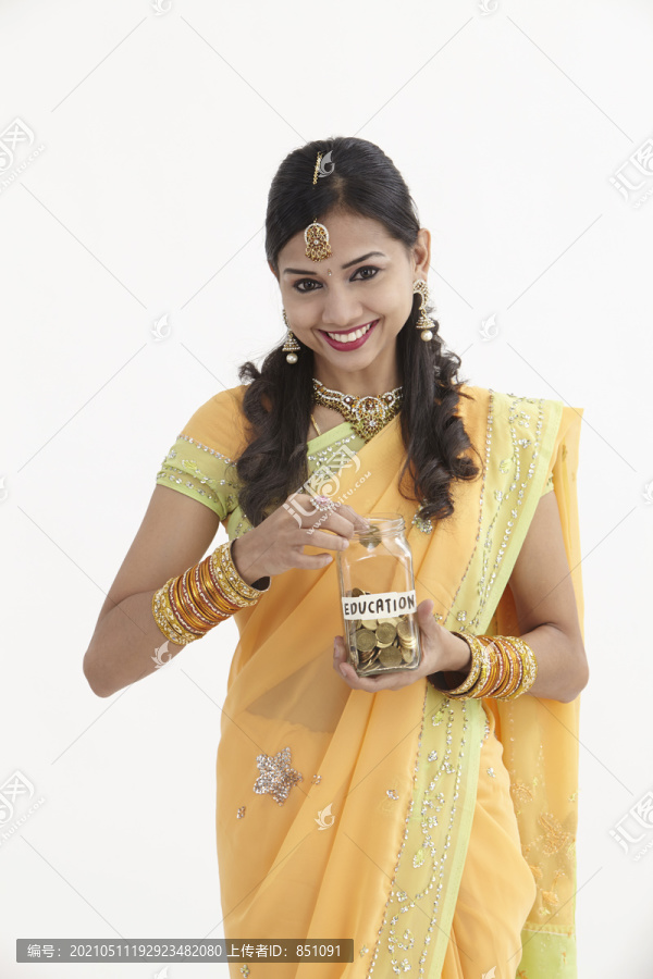 穿着迷人传统服装的印度女人手里拿着一个储蓄罐