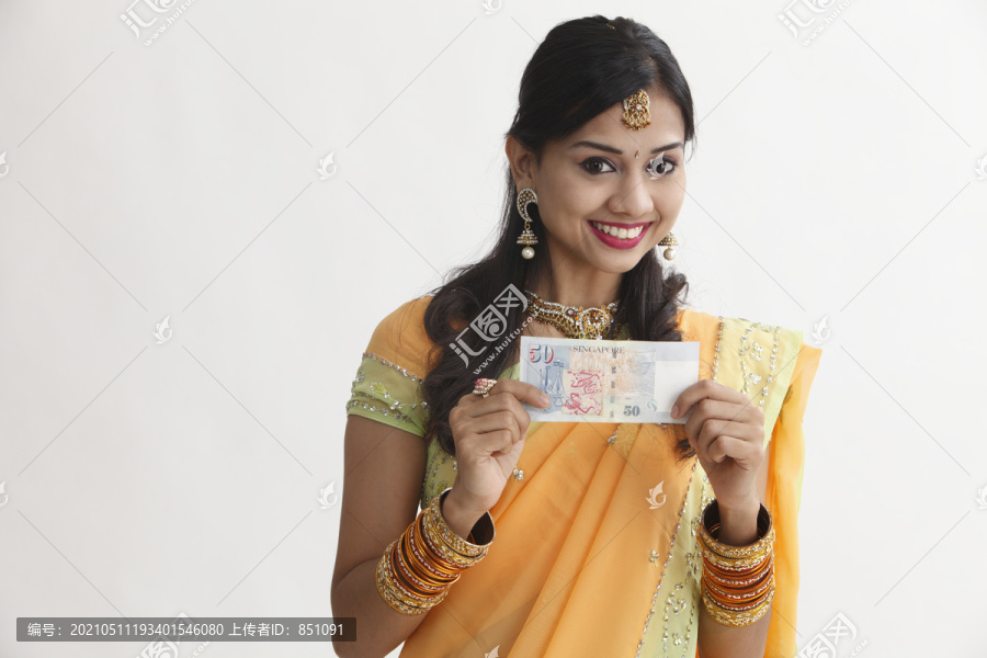 一个穿着纱丽的妇女手里拿着新加坡的钞票