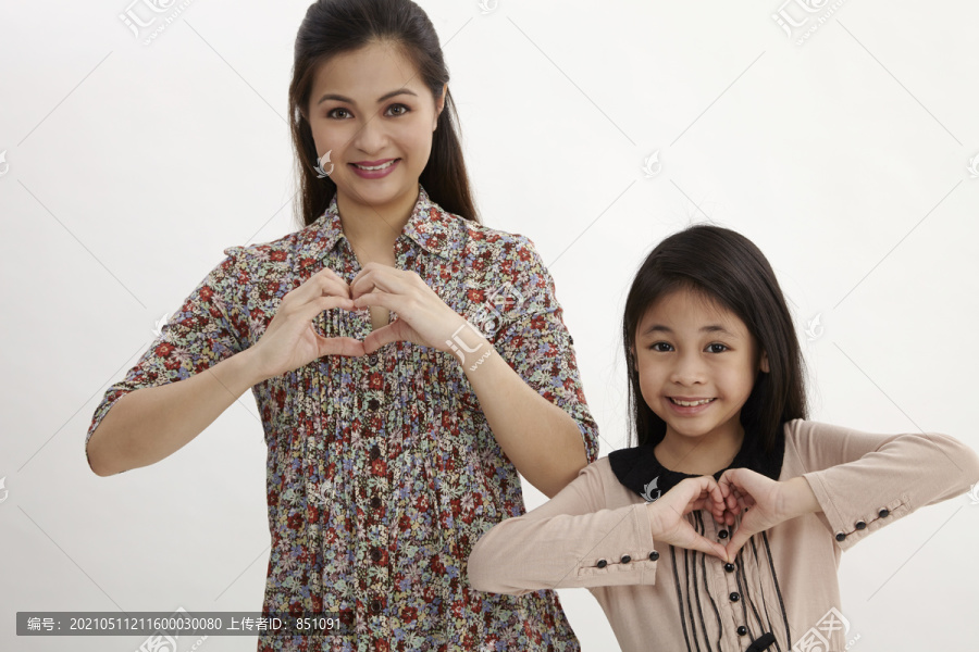幸福的母亲和小女儿的肖像，心形标志-隔离在白色背景上