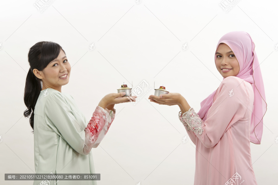 两名手持油灯或佩利塔的马来妇女