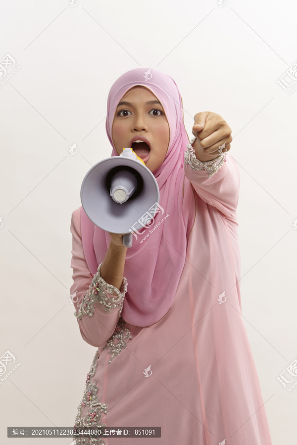 一名马来妇女对着扩音器讲话，在白色电视上发表公告