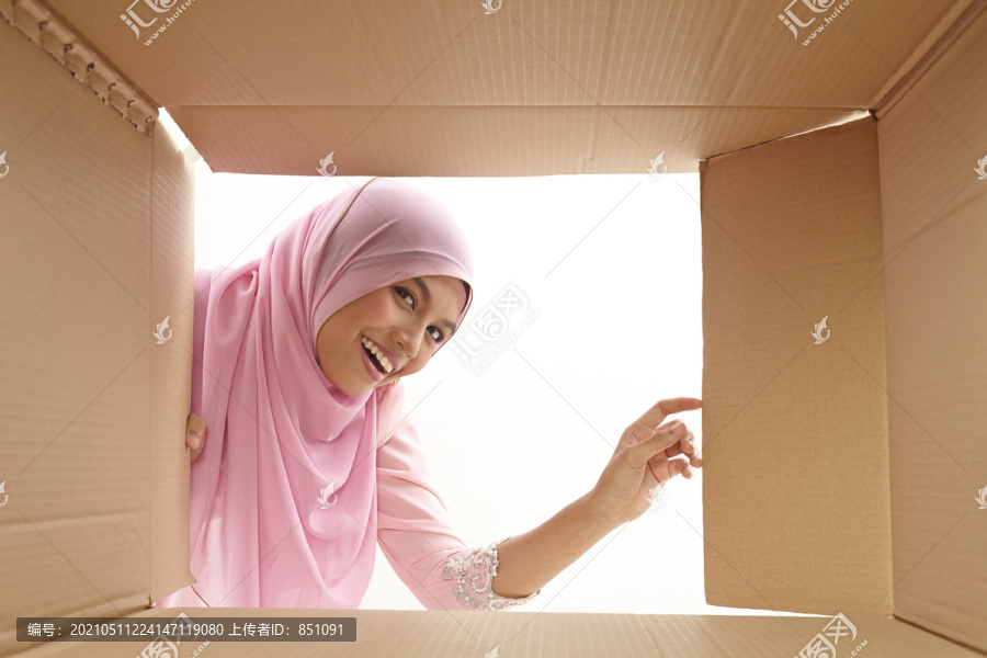 女人打开一个纸箱，看看里面，搬迁和开箱的概念