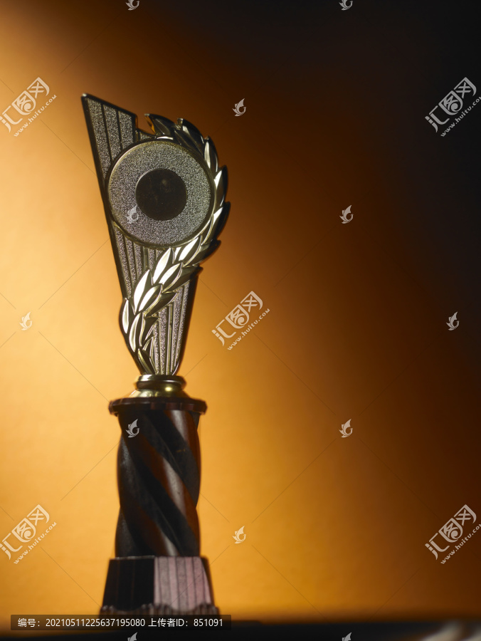 金色奖杯和奖牌放在橙色背景的桌子上。