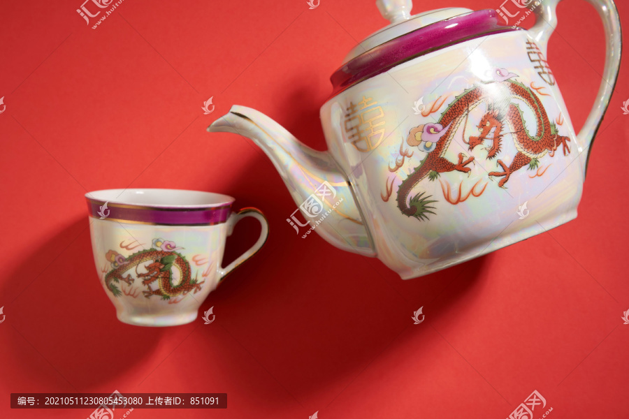 中国传统婚礼上使用的龙凤茶壶和茶杯，带有中国标志，寓意幸福。翻译：双喜临门