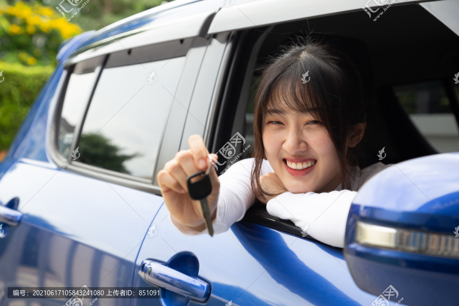 年轻快乐的亚洲汽车女司机微笑着出示新车钥匙。新手驾驶人概念