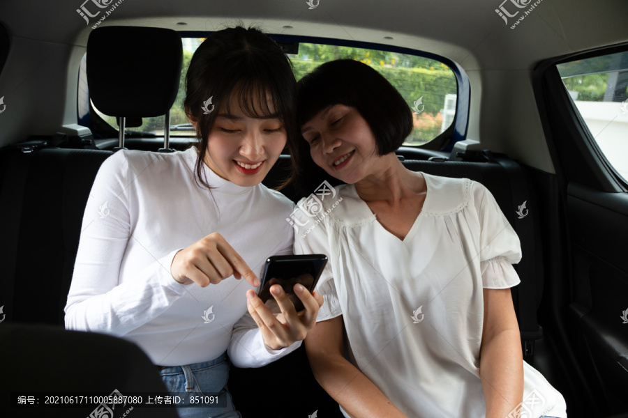 快活的亚洲母女坐在车里，抚摸着手机，外出旅行，还有不同年代的老年人和青少年的观念